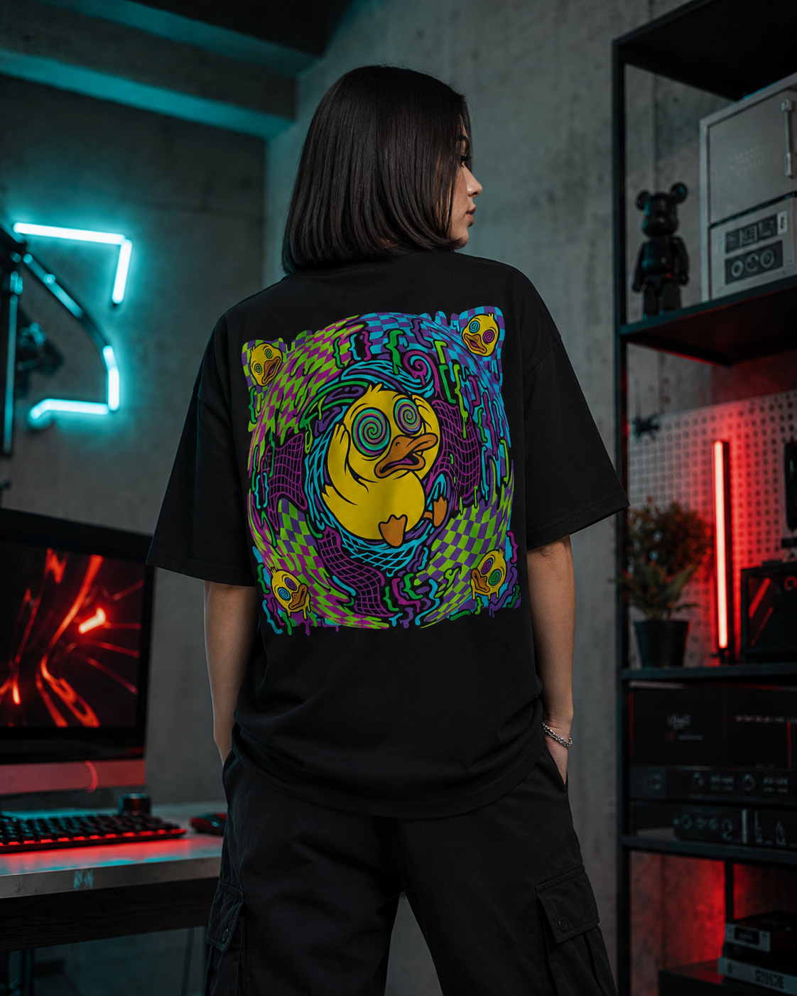 Modelo de espalda con la playera Me bugeé; el rubber duck entre glitches y colores neón ocupa toda la espalda