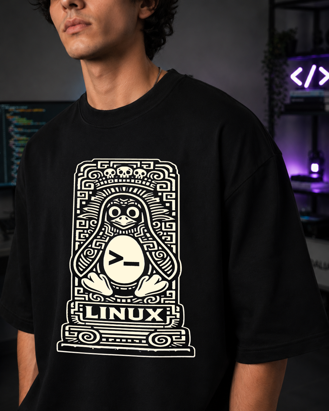 Modelo con la playera Linux oversize en primer plano; el pingüino tallado en estela ocupa todo el pecho