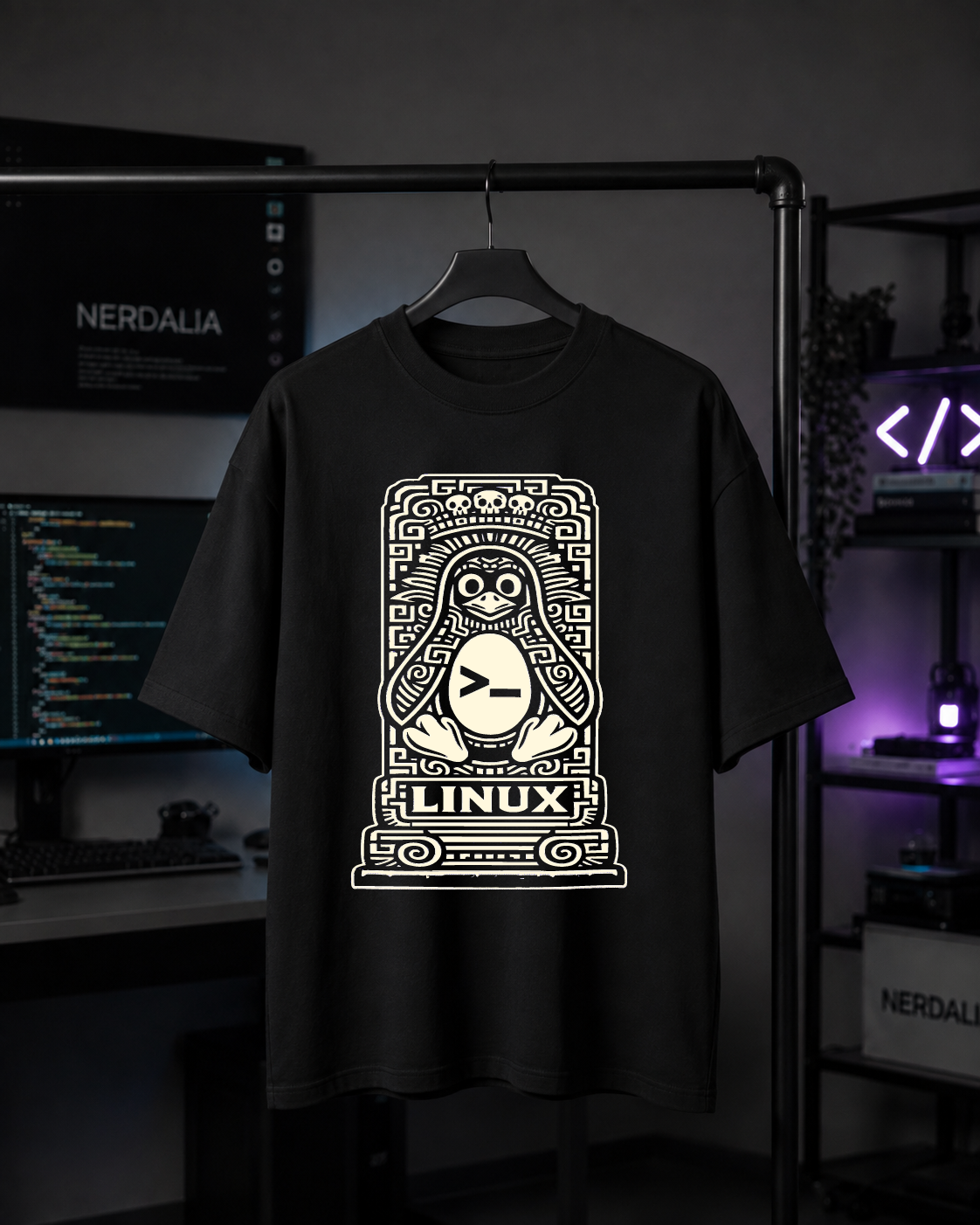 Playera Linux oversize colgada en un perchero frente a un setup de monitores